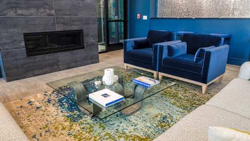 A living room with a fireplace and blue chairs.